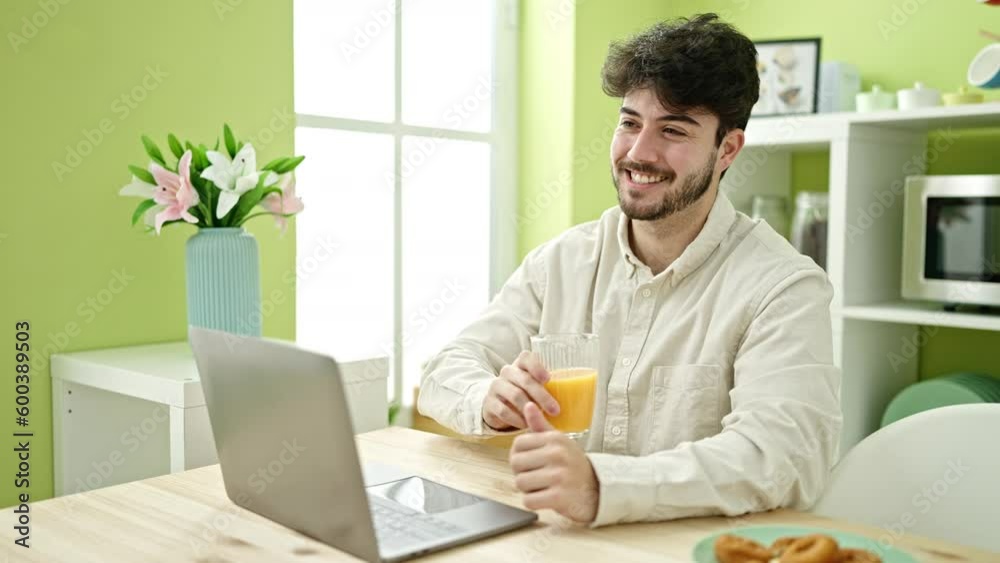 Young hispanic man having breakfast using laptop at dinning room Young hispanic man having breakfast using laptop at dinning room