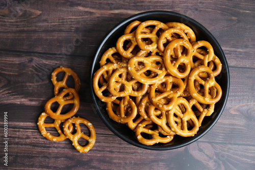 Crunchy pretzels in a black bowl are placed on a wooden table. A perfect salty party snack. copy space. crispy baked salt cookies or biscuits 