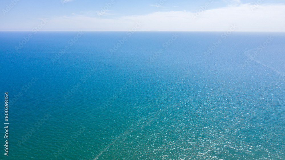  Aerial view of the blue waters of the Mediterranean Sea and specifically of the Tyrrhenian Sea. Sunlight is reflected on the surface of the water. Sky and clouds are on background.