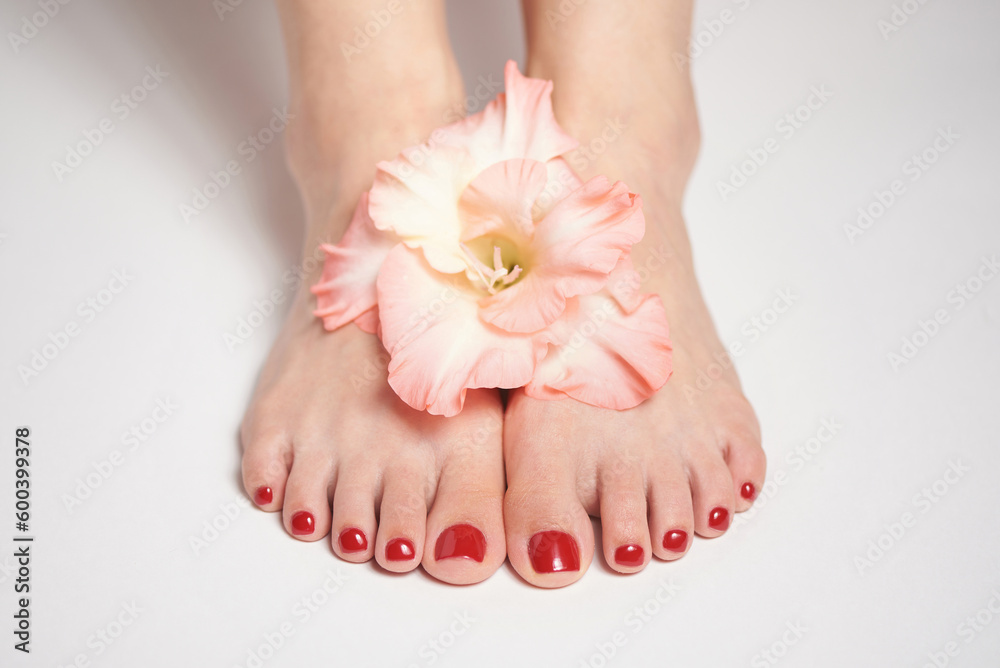 Feet with pedicure and flower, a concept of beauty and care Feet with pedicure and flower, a concept of beauty and care