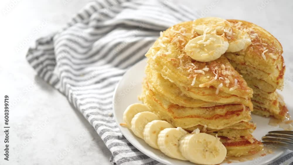 Eating freshly baked coconut banana pancakes garnished with sliced bananas and toasted coconut. Eating freshly baked coconut banana pancakes garnished with sliced bananas and toasted coconut.
