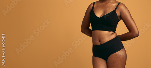 Crop black plus size woman in underwear against orange background