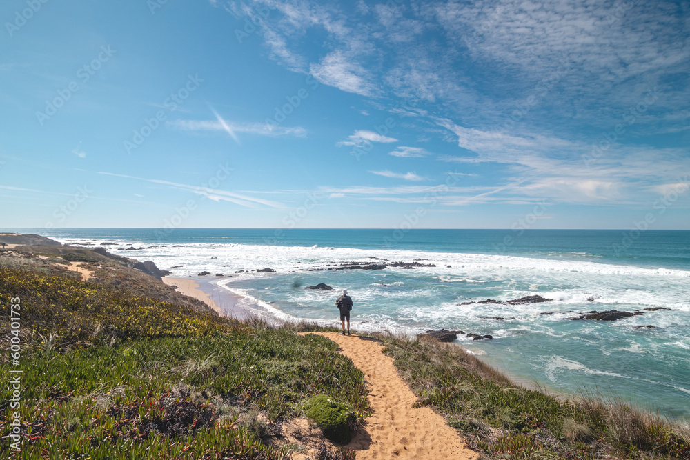 Traveler walks on a sandy path during a sunny day in Odemira region, western Portugal. Wandering along the Fisherman Trail, Rota Vicentina