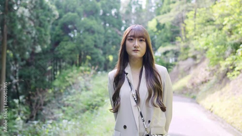 A young Japanese woman in her twenties, wearing a white jacket and shorts, admiring the beautifully blooming pink azaleas in a large nature park in Tsubata Town, Kahoku District, Ishikawa Prefecture. photo