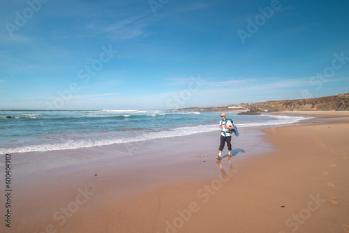 Backpacker walks along Praia do Almograve with a smile on his face. The joy of moving and discovering new places. Odemira region, western Portugal. Wandering along the Fisherman Trail, Rota Vicentina
