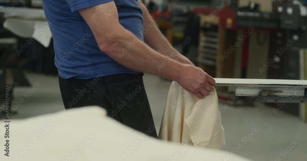 Man Places T Shirt on Screen Printing Machine Man Places T Shirt on Screen Printing Machine