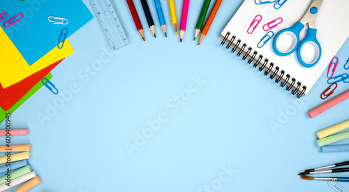 Colorful school supplies lie in the form of a frame on blue background. Back top school concept. Copy space. Flatlay composition. Top view.