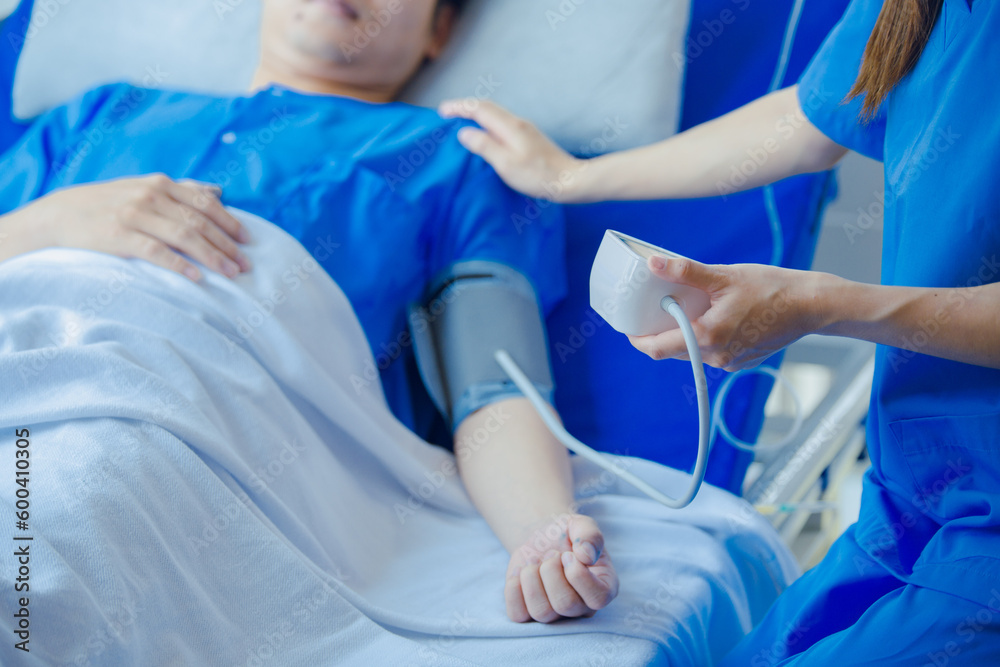Female doctor using blood pressure monitor and stethoscope to check blood pressure on male patient in hospital. Female doctor using blood pressure monitor and stethoscope to check blood pressure on male patient in hospital.
