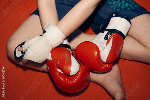 Top view teen boy putting on red boxing gloves before training