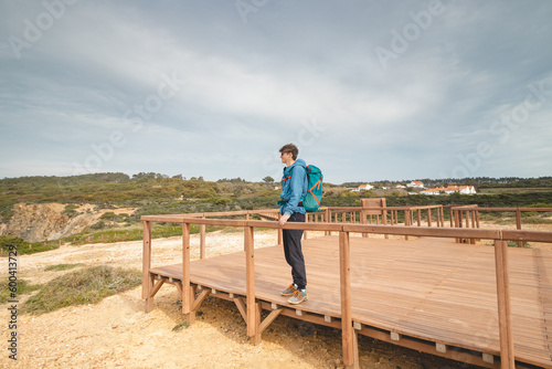 Young and adventurous Vagabond wandering the Portuguese countryside on the Fisherman Trail enjoys the views of the Atlantic Ocean at a lookout point. Odemira region, Rota Vicentina