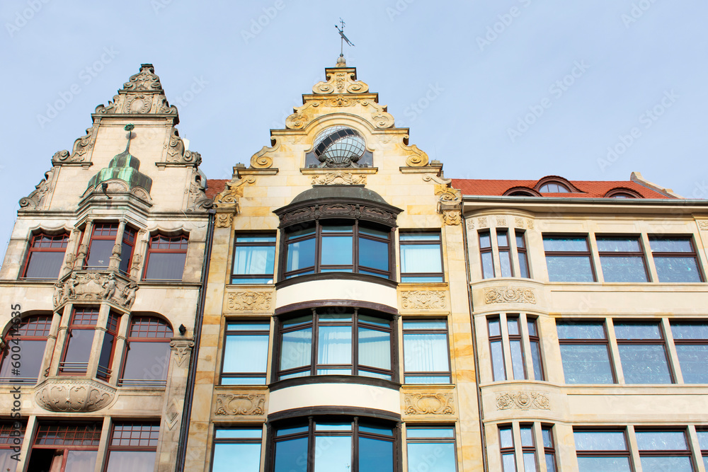 Obraz premium Facade of an ancient architectural buildings with yellow walls, wide windows, decorative elements and red roof. Historical architecture. Old town. Poland, Wroclaw, January 2023.