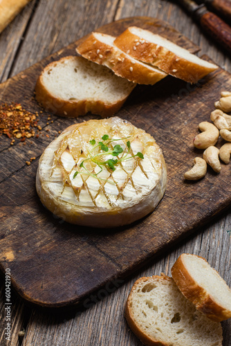 Baked Camembert cheese on a wooden board. Baguette