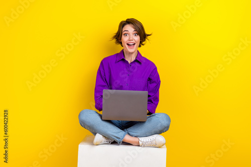 Full lenght photo of lovely young lady netbook sitting cube wear trendy violet smart casual garment isolated on yellow color background