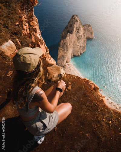 adventurous girl looking at the spectacular cliffs and turquoise waters of the Greek island of Zakhyntos during her sightseeing tour of the Ionian islands