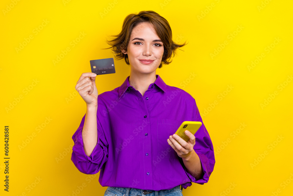 Photo portrait of attractive young woman hold credit card gadget wear trendy violet smart casual outfit isolated on yellow color background Photo portrait of attractive young woman hold credit card gadget wear trendy violet smart casual outfit isolated on yellow color background