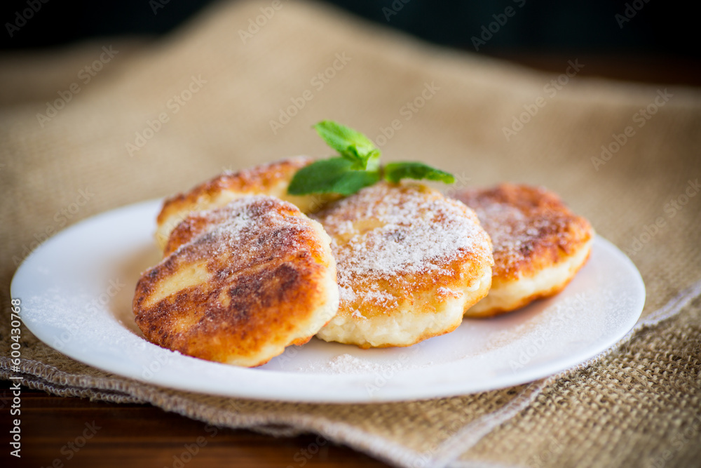 Sweet cooked cheesecakes in powdered sugar in a plate