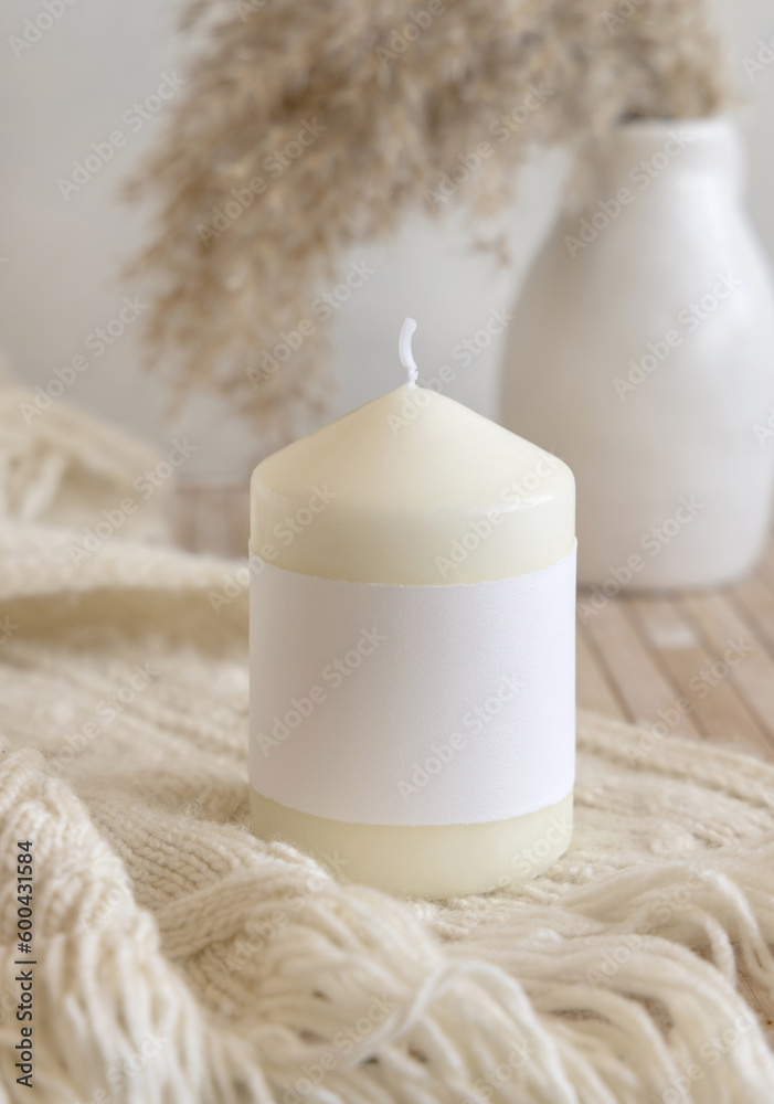Candle with label on cosy sweater near dry pampas grass, Close up, mock up