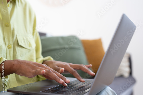 African female employee working at laptop  typing on keyboard. Woman hands close up. Businesswoman in casual  professional working at table  using online app  chatting  writing article. Cropped shot.