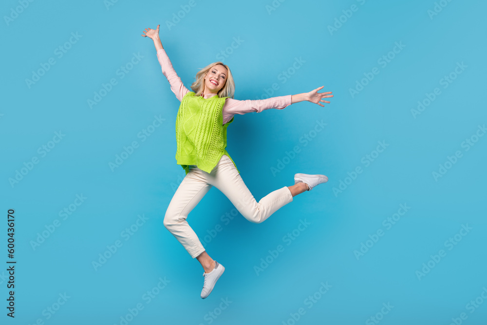 Full size photo of cheerful nice girl jumping have good mood rejoice isolated on blue color background Full size photo of cheerful nice girl jumping have good mood rejoice isolated on blue color background