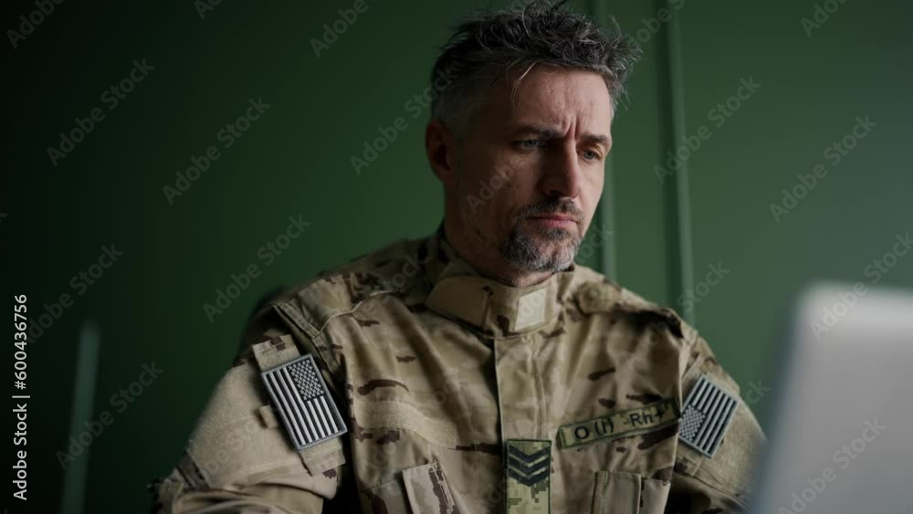 Soldier working with laptop in home. Everyday life of a military man in reserve. Work and communication online Soldier working with laptop in home. Everyday life of a military man in reserve. Work and communication online