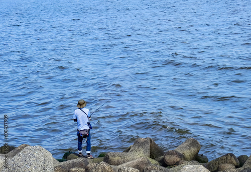 海の磯で魚釣りをする人