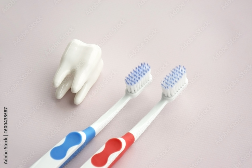 Toothbrushes with a small figure of a tooth on a light background. Toothbrushes with a small figure of a tooth on a light background.