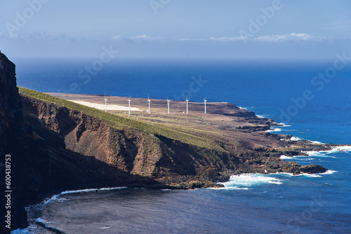 Alternative energy on the island. Several wind turbines stand on the shore against the background of the ocean photo