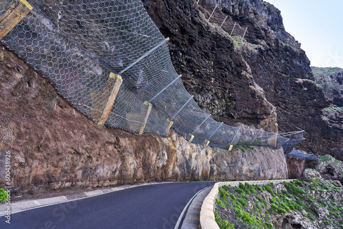 A dangerous road in the mountains where landslides often occur. Safety net against falling rocks in the rock