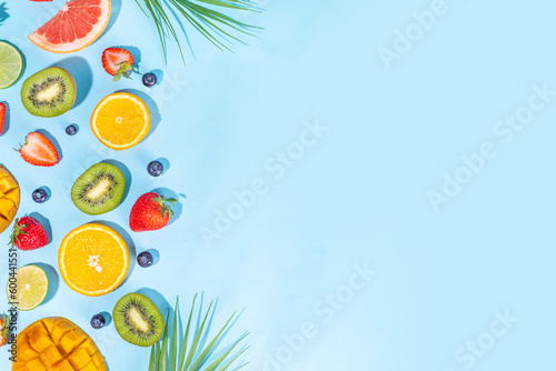 Summer vitamin food concept, various fruit and berries mango peach mint plum apricots blueberry currant, creative flat lay on light blue background top view copy space