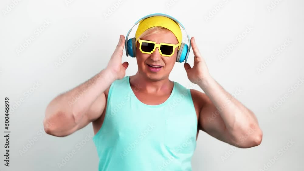 DJ guy dancing having fun, rhythm to music, enjoying entertainment. Excited man dance in sunglasses, having fun in yellow beanie, blue tank top. Nightclub, party, streaming service, online radio app DJ guy dancing having fun, rhythm to music, enjoying entertainment. Excited man dance in sunglasses, having fun in yellow beanie, blue tank top. Nightclub, party, streaming service, online radio app