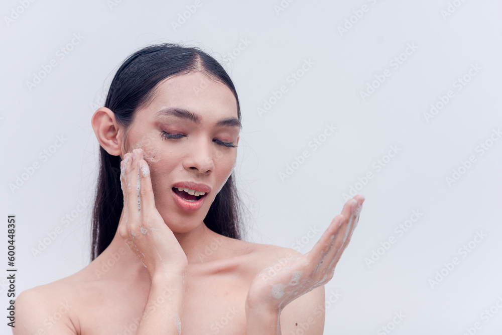 Pretty transgender lady washes her face with soapy hands. Studio shot isolated on a white background. Beauty products and cosmetics endorser. Pretty transgender lady washes her face with soapy hands. Studio shot isolated on a white background. Beauty products and cosmetics endorser.