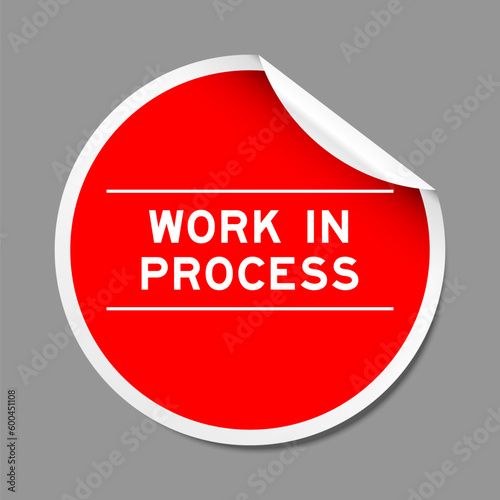 Red color peel sticker label with word work in process on gray background