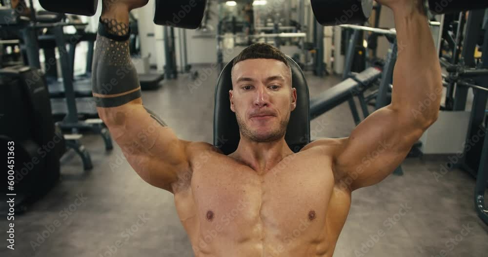 Muscular bodybuilder man lifting heavy weights black dumbbells. One full set of exercises