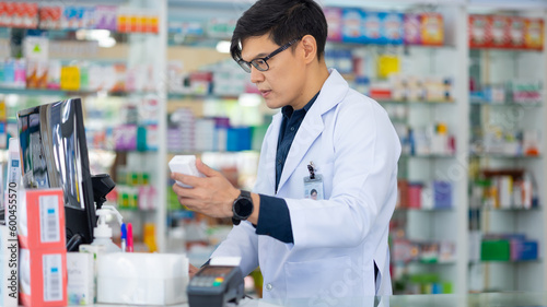 Male working on computer. Pharmacy Drugstore. Portrait Professional Pharmacist handsome asian man at pharma store. Health and wellness center