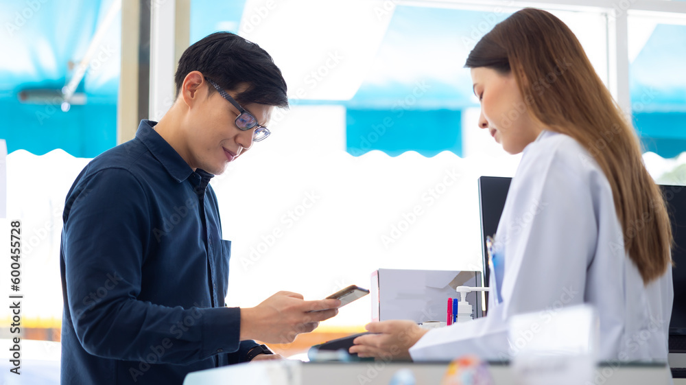 Professional Pharmacist handsome asian man holding bank payment terminal machine for customer payment on creditcard. Pharmacy Drugstore. Health and wellness center Professional Pharmacist handsome asian man holding bank payment terminal machine for customer payment on creditcard. Pharmacy Drugstore. Health and wellness center