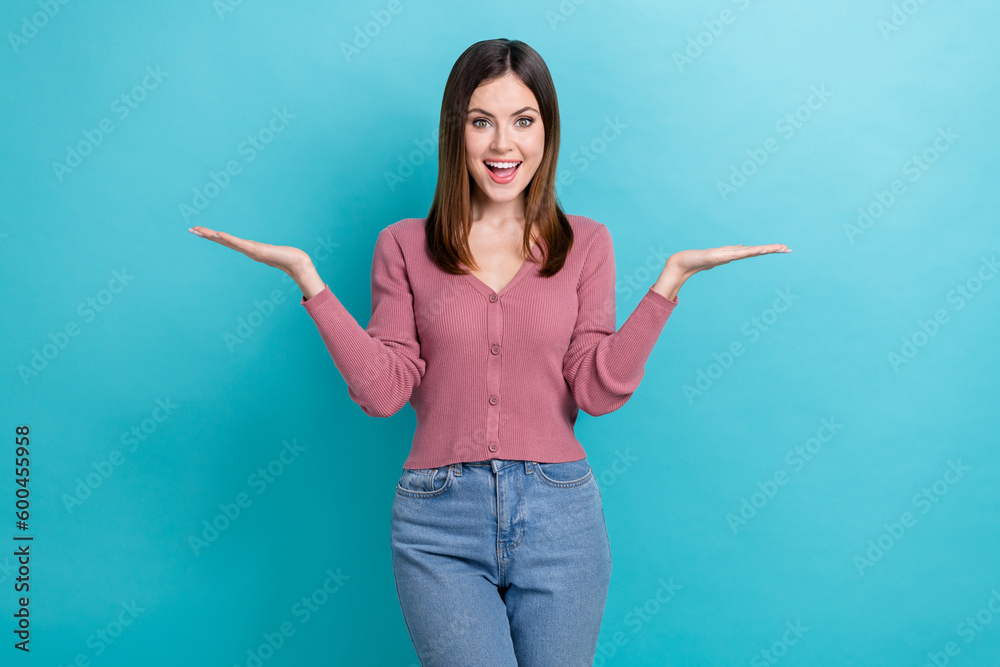 Photo of ecstatic impressed girl straight hairdo pink cardigan arms comparing objects empty space isolated on blue color background Photo of ecstatic impressed girl straight hairdo pink cardigan arms comparing objects empty space isolated on blue color background