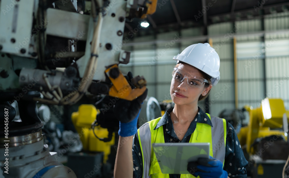 A female engineer installs a program on a robotics arm in a robot warehouse. And test the operation before sending the machine to the customer. A female engineer installs a program on a robotics arm in a robot warehouse. And test the operation before sending the machine to the customer.