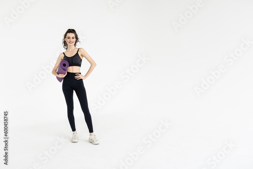 Sports woman holding a fitness mat in her hands on a white background