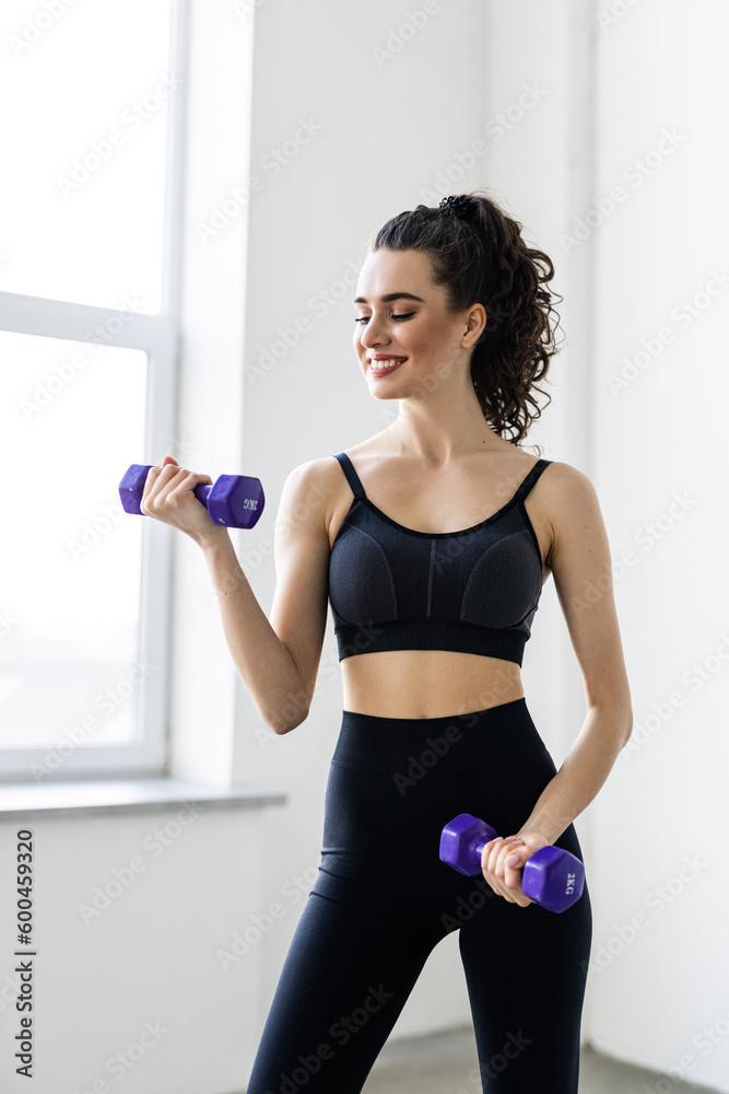 fitness, sport and healthy lifestyle concept. Smiling young woman with dumbbells exercising at home
