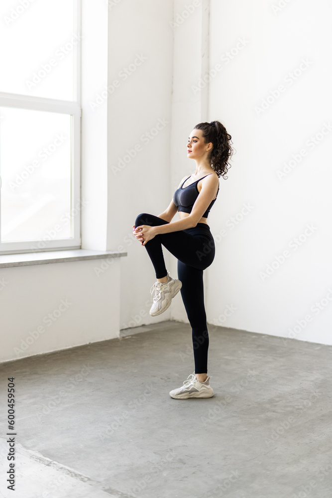 Young woman exercising at home, stretching legs in living room Young woman exercising at home, stretching legs in living room