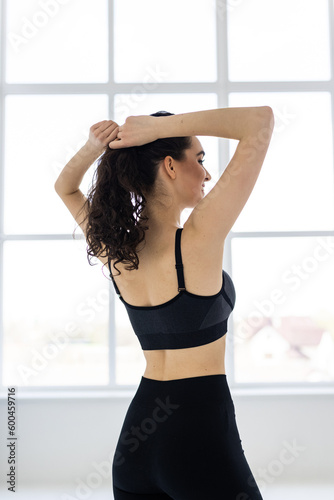 Sporty slim woman with ponytail fitness woman enjoys workout exercise in purple sport wear on gray background