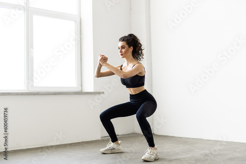 Young beautiful woman squats at home