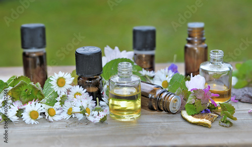 few essential oil bottles with flowers on a table  on green background