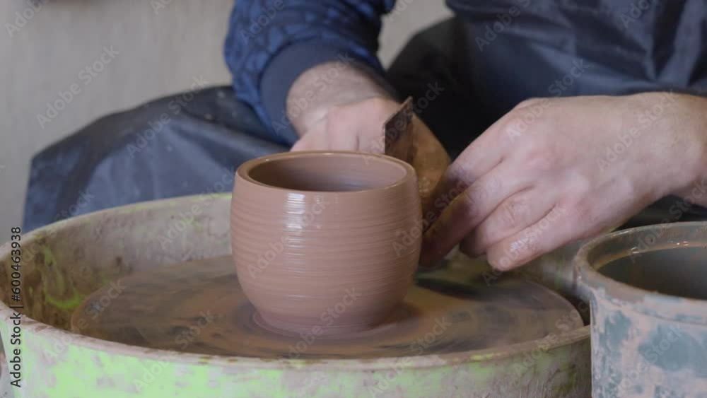 Close up hands of a ceramist using potter's wheel to make a cup Close up hands of a ceramist using potter's wheel to make a cup
