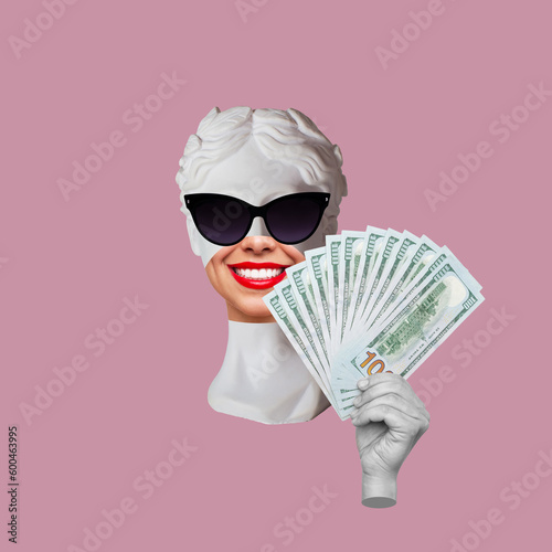 Fotografia Antique female smiling statue's head in black sunglasses holds a wad of hundred-dollar cash banknotes pink color background