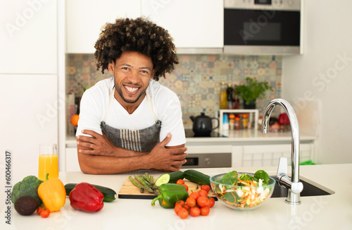 Cheerful african american guy posing at kitchen table at home
