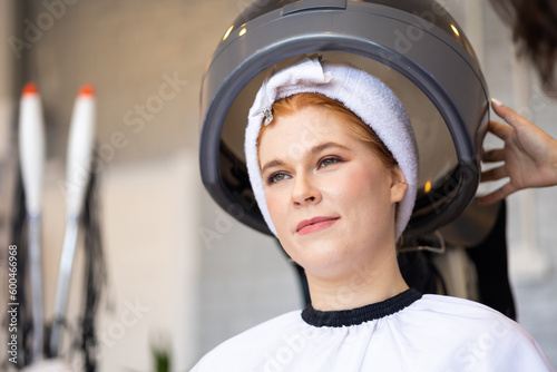 Beautiful caucasian woman red hair under hair steaming at beauty salon shop