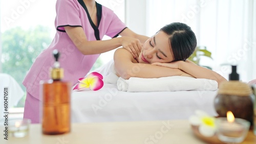 Healthy and beautiful Asian woman in white towel lying on spa bed closed eyes relaxing receiving neck and shoulders massage. Spa treatment concept