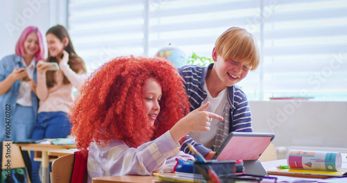 Wallpaper Mural Side view of boys and red haired girl talking and using digital tablet during break in school. Happy classmates in casual attire discussing funny video in bright classroom. Torontodigital.ca