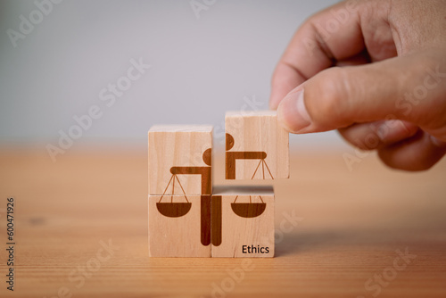 Concept of business ethics and moral principles, as a hand holds wooden cubes with 